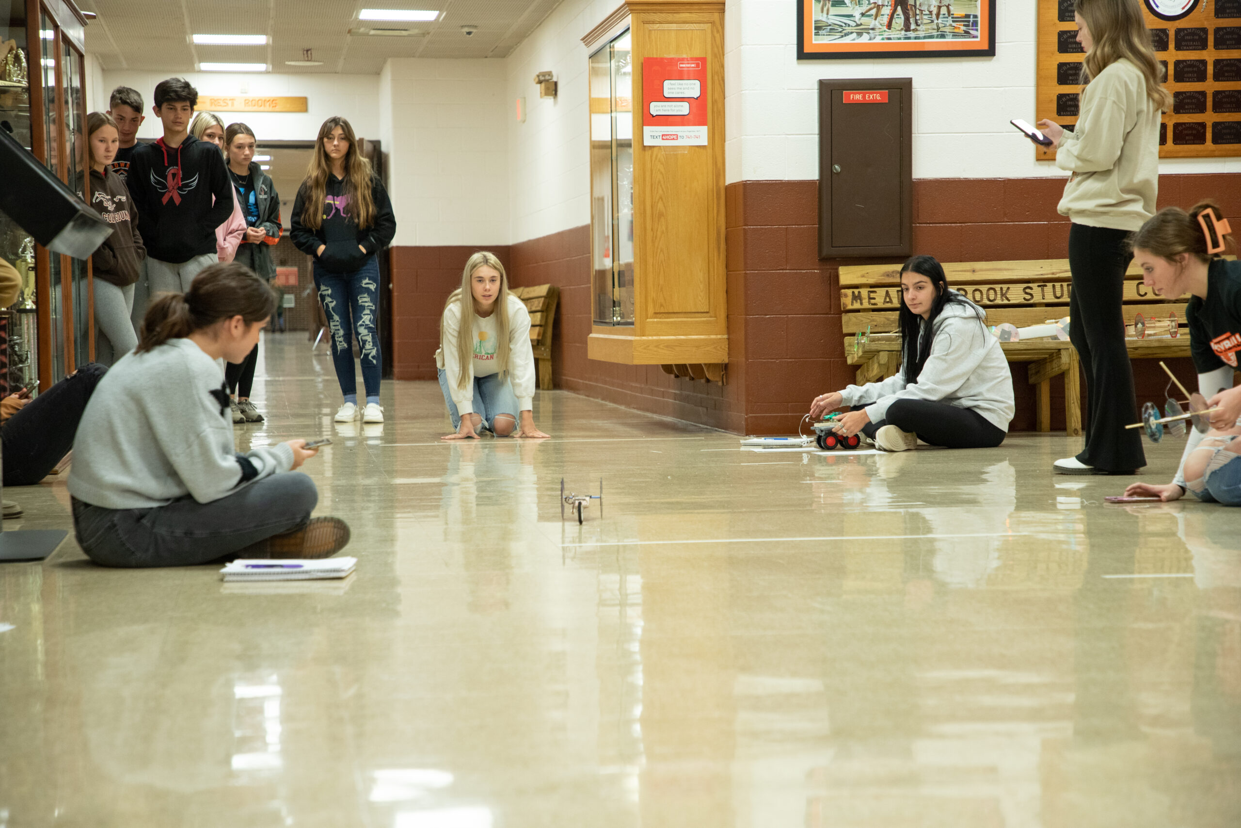 Kids using iPads on the floor of the school hallway